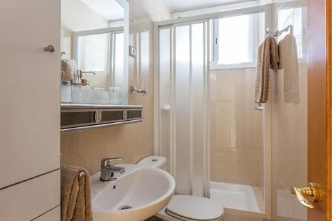 Simple style interior of small restroom with beige ceramic tile walls, white Stock Photos