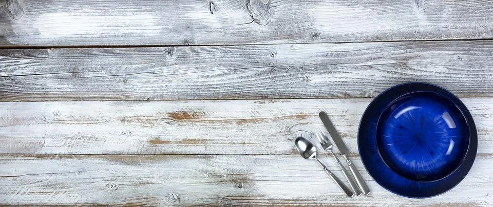 Simple table setting of an empty main dark blue dish and bowl with cutlery .. Stock Photos