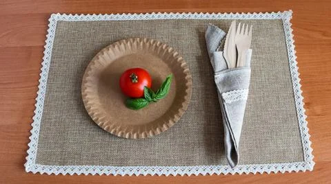 Simple table setting with a plate, tomato, and cutlery on a placemat Stock Photos