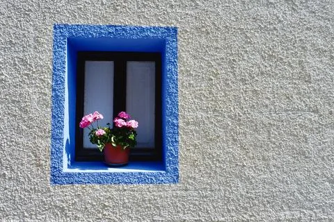 Simple tiny window with flower on rustic house wall of white and blue colou.. Stock Photos