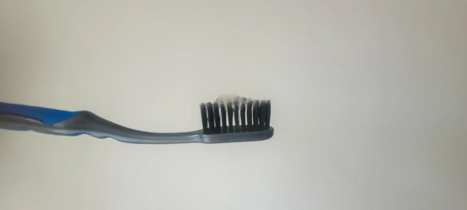 Simple toothbrush standing upright with toothpaste on the bristles against .. Fotos Stock