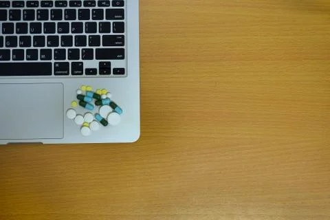 Simple top view of computer have medicine drug pills and tablet on keyboard w Stock Photos