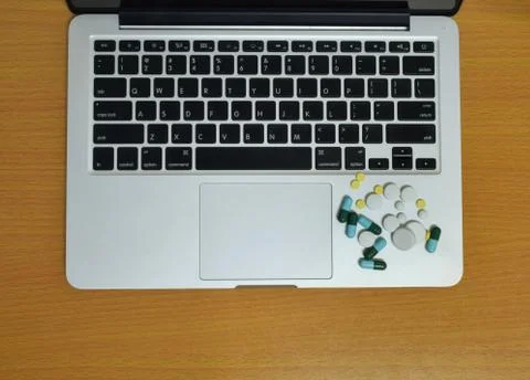 Simple top view of computer have medicine drug pills and tablet on keyboard w Stock Photos
