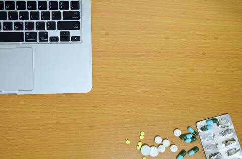 Simple top view of computer with medicine drug pills and tablet on wooden bac Stock Photos