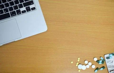 Simple top view of computer with medicine drug pills and tablet on wooden bac Stock Photos
