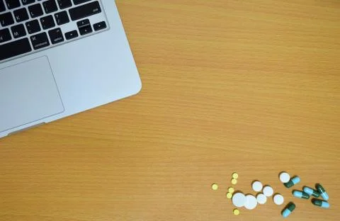 Simple top view of computer with medicine drug pills and tablet on wooden bac Stock Photos