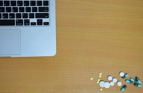 Simple top view of computer with medicine drug pills and tablet on wooden bac Stock Photos
