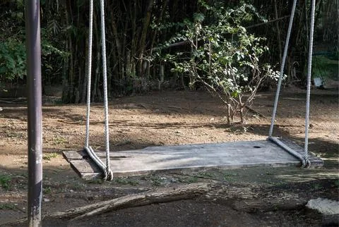 A simple, weathered swing hangs in repose, inviting a moment of rest beneat.. Stock Photos