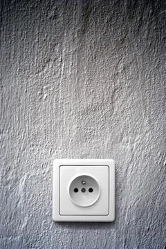 Simple white electric socket on grey wall Stock Photos