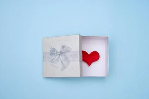 Simple white open gift box isolated on blue background. Red heart in box. Stock Photos
