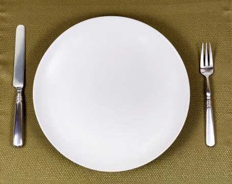 Simple white plate with silverware for dinner setting on table cloth Stock Photos