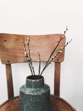 Simple willow buds branches in stylish vase on wooden rustic chair in home. H Stock Photos