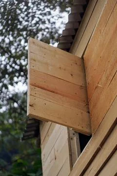 Simple wooden shutter window opened on a plank wall cabin house in the forest Stock Photos