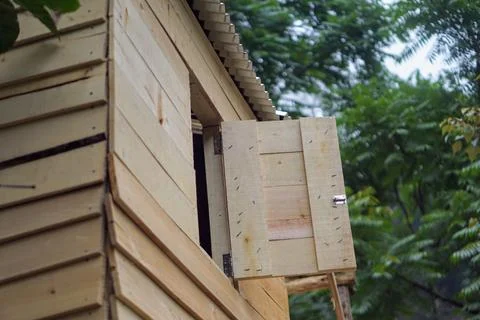 Simple wooden shutter window opened on a plank wall cabin house in the forest Stock Photos