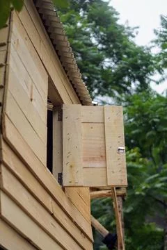 Simple wooden shutter window opened on a plank wall cabin house in the forest Stock Photos