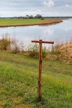 Simple wooden T-post by a calm riverside landscape Stock Photos
