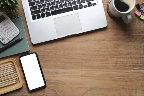 Simple workplace with laptop computer, coffee cup, potted plant and stationer Stock Photos
