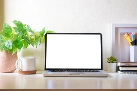 Simple workplace with laptop, cup of coffee, picture frame and houseplant o.. Stock Photos