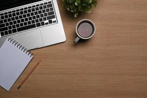 Simple workspace with laptop computer, coffee cup and notepad on wooden table. Foto stock