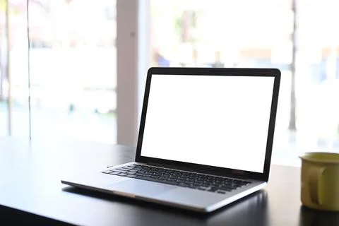 Simple workspace with mock up laptop computer with blank screen and coffee cu Stock Photos