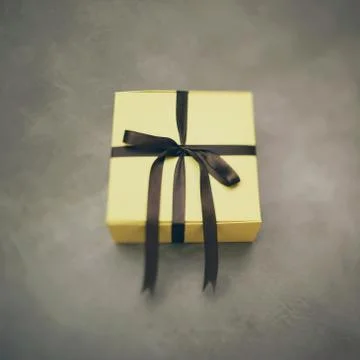 Simple yellow square box wrapped in a ribbon for a gift Photos