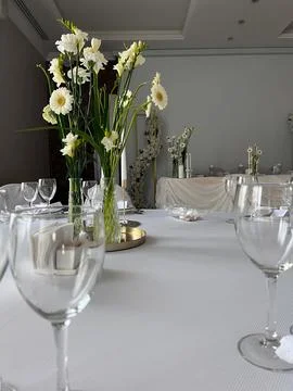 Simple yet elegant table setting featuring white flowers and clear glassware. Stock Photos