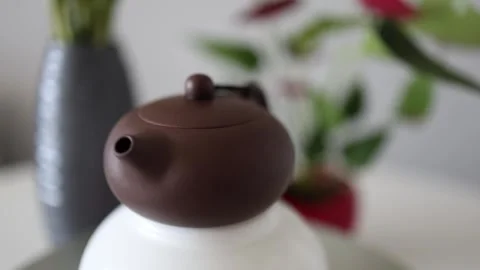 A simple yet elegant Yixing teapot sits gracefully on a white surface. Its smoot Stock Footage 304623291
