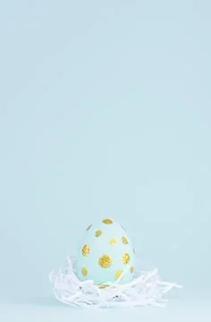 Simplicity and minimal design of easter egg with gold in white nest on blue b Stock Photos