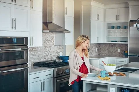 Simplifying the baking experience with smart technology. a young woman using a Stock Photos