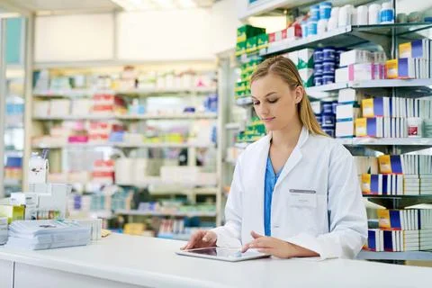 Simplifying pharmaceutical tasks with smart technology. a young pharmacist using Stock Photos