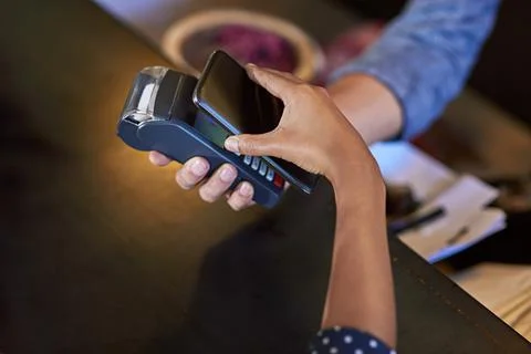Simplifying spending. a woman paying using NFC technology in a cafe. Stock Photos