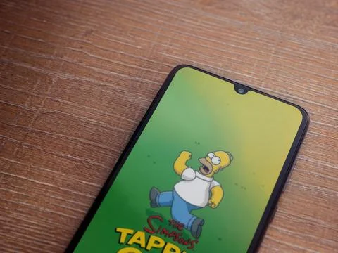 The Simpsons Tapped Out app launch screen on smartphone on wooden background Stock Photos