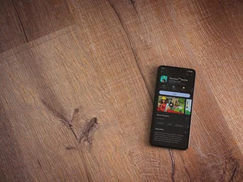 The Sims Mobile app play store page on smartphone on wooden background Stock Photos
