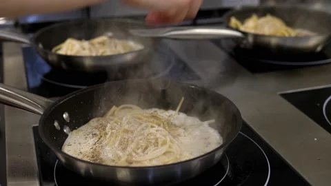 Simultaneous cooking and mixing of spaghetti with cream sauce in several pans. Stock Footage 171767141