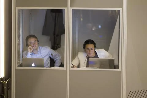  Simultaneous interpreters work in a glassed-in booth. Stock Photos