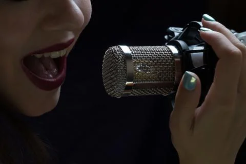 Singer in front of a microphone. Isolated on a dark background Stock Photos