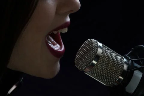 Singer in front of a microphone. Isolated on a dark background Stock Photos