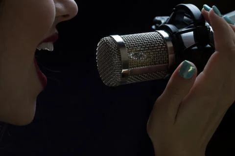 Singer in front of a microphone. Isolated on a dark background Stock Photos