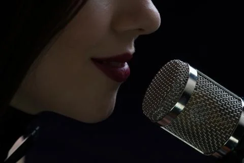 Singer in front of a microphone. Isolated on a dark background Stock Photos