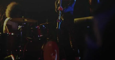 Singer in patterned pants performing on stage holding mic stand, with red drum Stock Illustration
