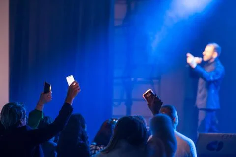 Singer performs on stage with audience holding up lights Stock Photos
