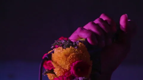A singer's hand holds a flower-decorated microphone on stage with pinkish hue Stock Footage