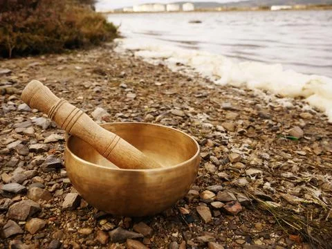 Singing bowl set on a pebble beach with the sea in background Stock Photos