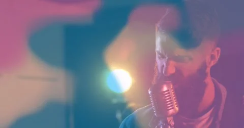 Singing camera-cue vocalist in jacket stepping into retro mic on stage with Stock Footage 333901063