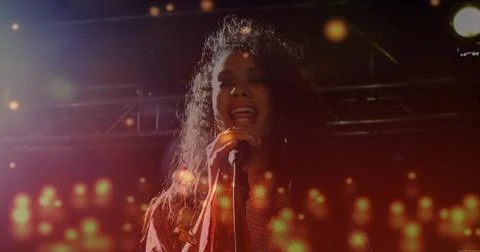 Singing solo singer wearing patterned jacket at concert, with handheld Stock Photos