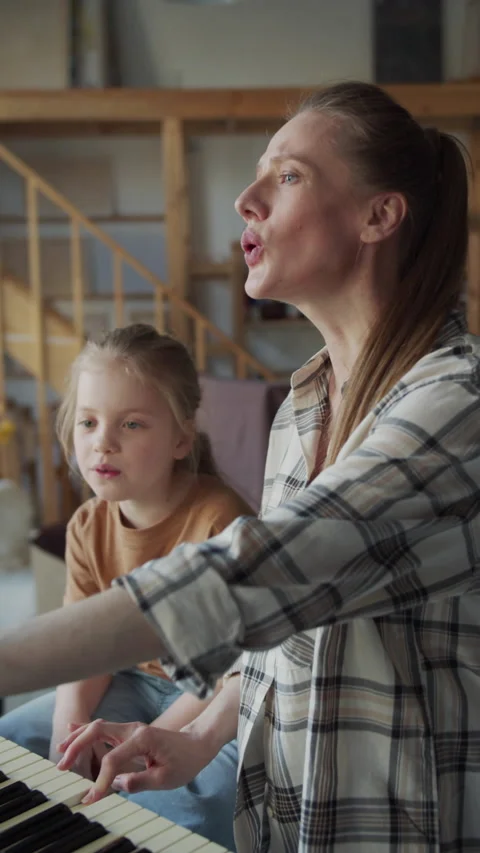 A singing tutor takes care of a young student. Woman presses the piano keys and Stock Footage 172675017