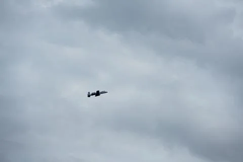 A single A-10 flying during a cloudy day Stock Photos