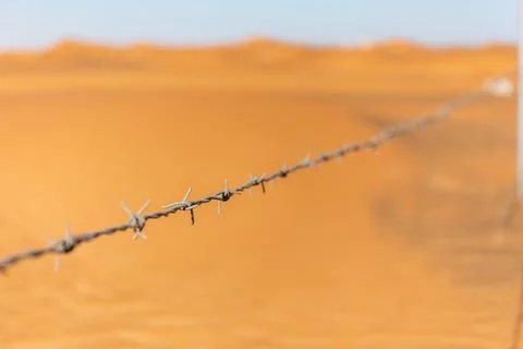 Single barbed wire with desert dunes in the background in Al Madam, UAE Fotos de archivo