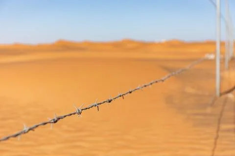 Single barbed wire with desert dunes in the background in Al Madam, UAE Fotos de archivo