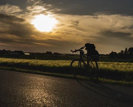 Single bicycle standing in front of the field during sunset Stock Photos